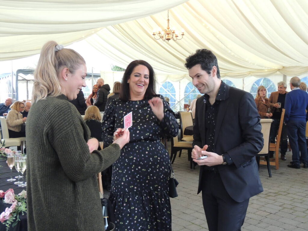 close hand magician performing to two women at a party