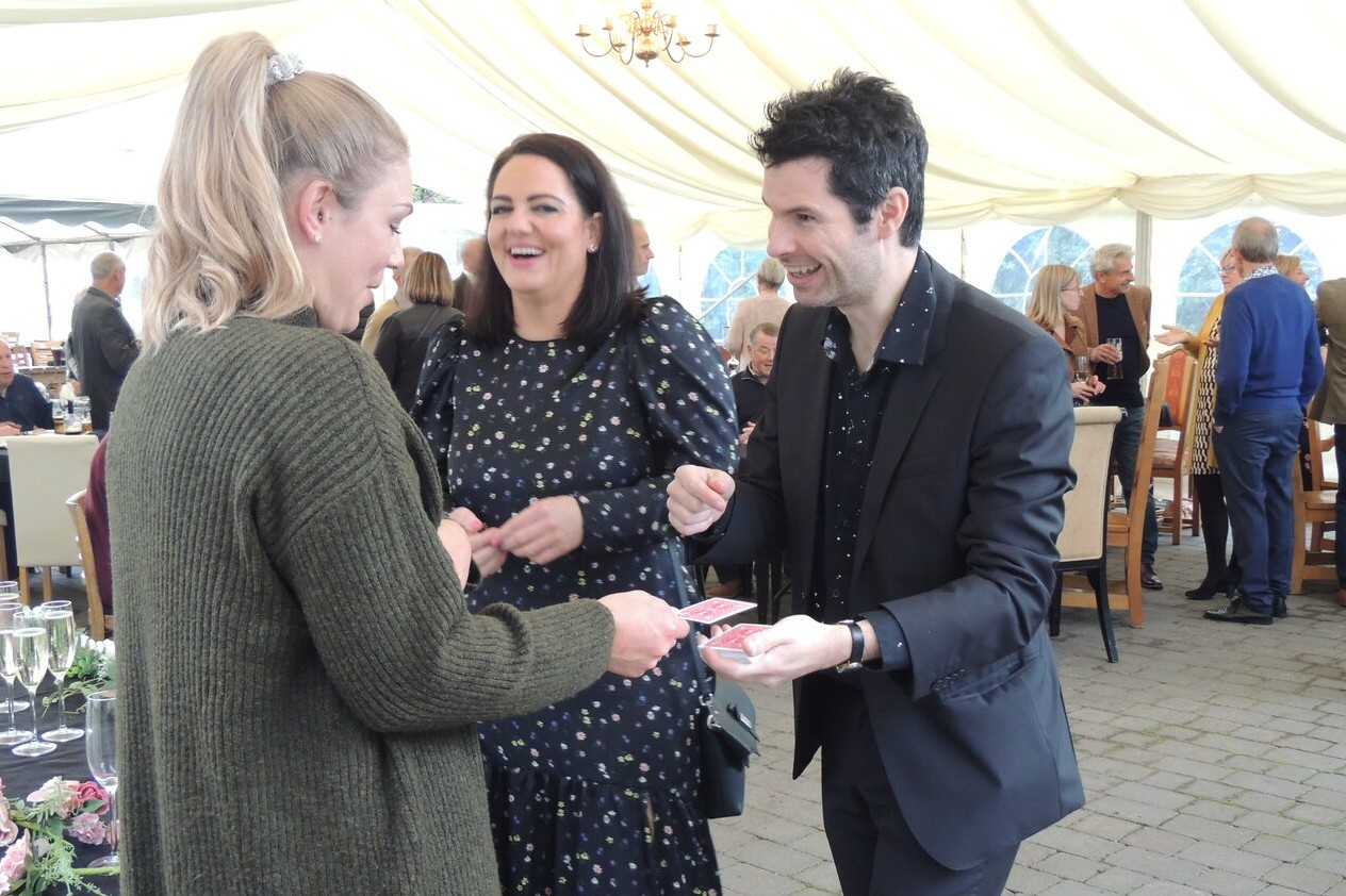 close up magician making visitors laugh in a festival tent