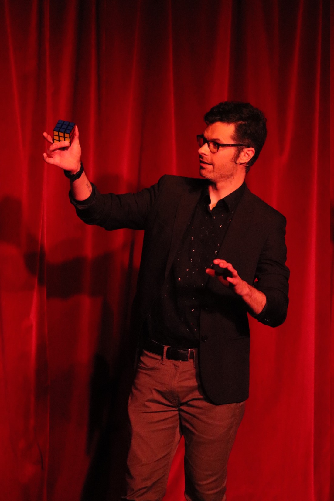 stage magician performing on stage with a rubik's cube